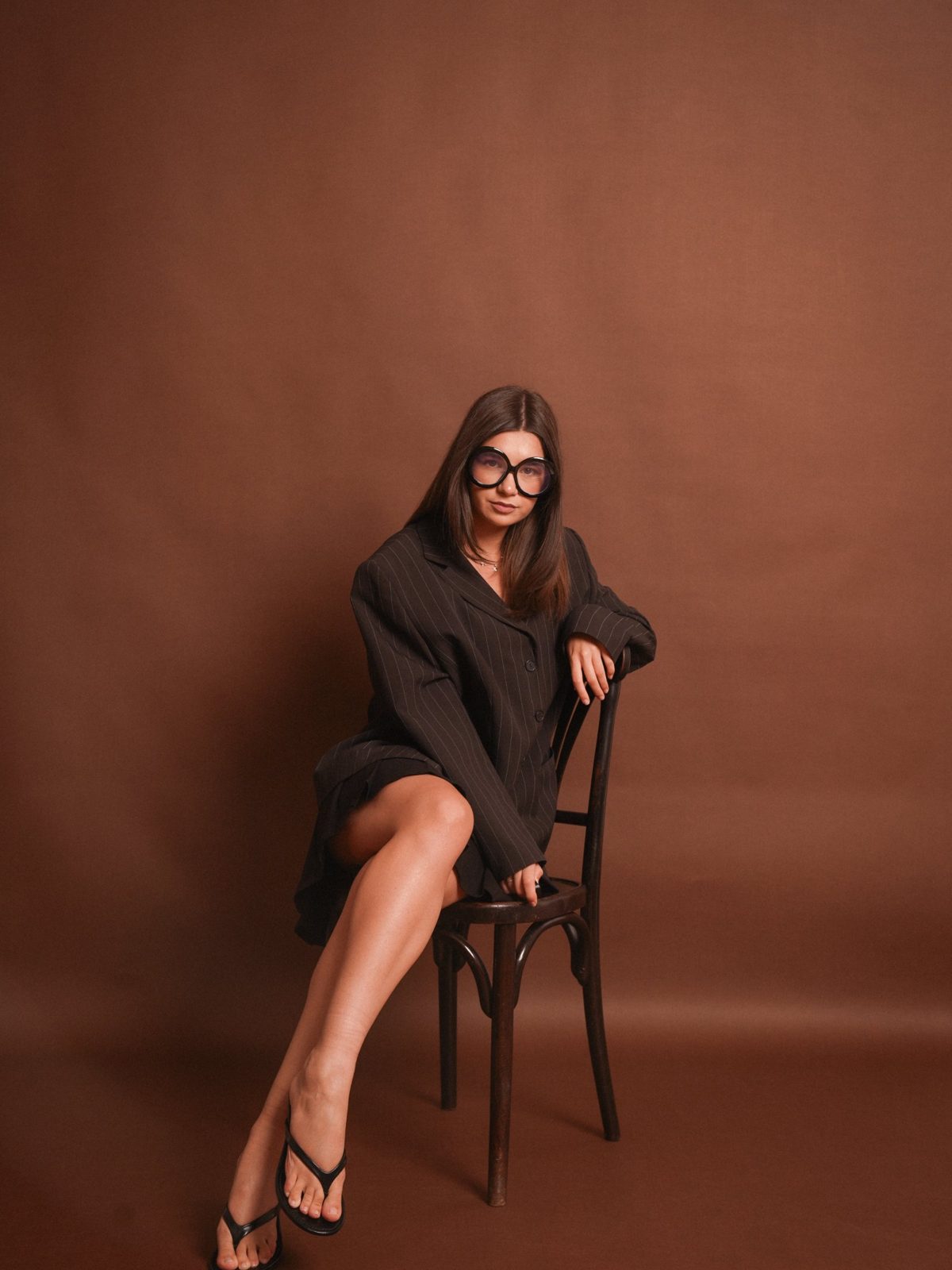 Portret pe scaun, sacou oversized, fundal maro